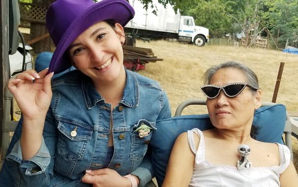 Gina, wearing my purple hat, with Baby Yoda in her denim jacket left pocket. Mom's beside her; wearing my rhinestone cateye sunglasses, with alien figurine sitting in her shirt.