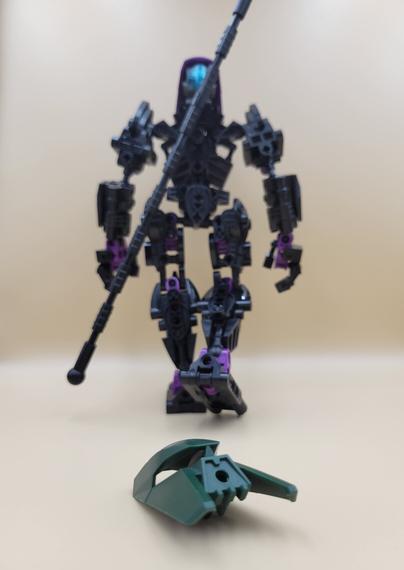 The same creation, now walking away from the camera, with a green version of its mask lying on the ground behind it. This mask was worn by the previous version of my self-MOC.