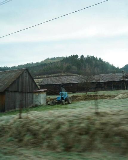 Masha Reva, road series made when the artist left Uzhhorod (Ukraine) for Berlin, April 2022 // Rolling countryside, farm buildings and one blue tractor, filmed from a moving vehicle. // Маша Рева, роуд-серия, сделанная при отъезде из Ужгорода в Берлин, конец апреля 2022 года // Холмистая сельская местность, аграрные постройки и один синий трактор, снятые из движущегося автомобиля.