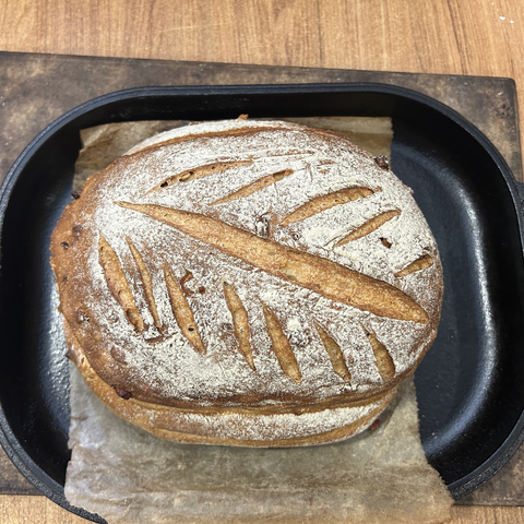 Closeup from above of the finished bread, still in the oven bread pan. It has a beautiful dark colour, with bits of white in between frim the last dusting with flour, before I cut the leaf pattern in the too of the dough. A very impressive looking bread.