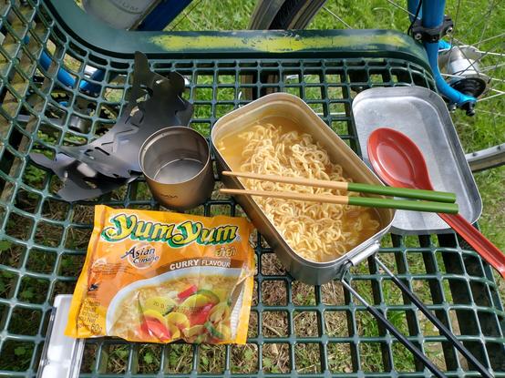 Eine fertig gekochte asiatische Nudelsuppe mit Camping-Kochutensilien