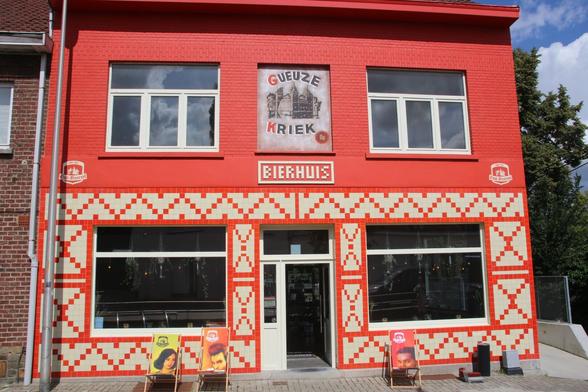 Exterior view of a two storey building with a symmetrical frontage. The lower half is decorated with red & white glazed tiles in geometric patterns. Above the door the same tiles are used to spell out "BIERHUIS".