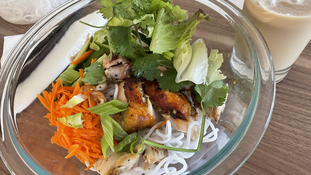 Thin bright -white rice, noodles with grilled chicken, cilantro, green onions, grated carrot, lettuce, and peanuts ￼. Served with a tall glass of Creme Brulé milk tea ￼