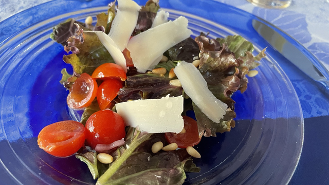 Red leaf lettuce salad with bright red cherry tomatoes, and cream-colored Parmesan cheese shavings ￼