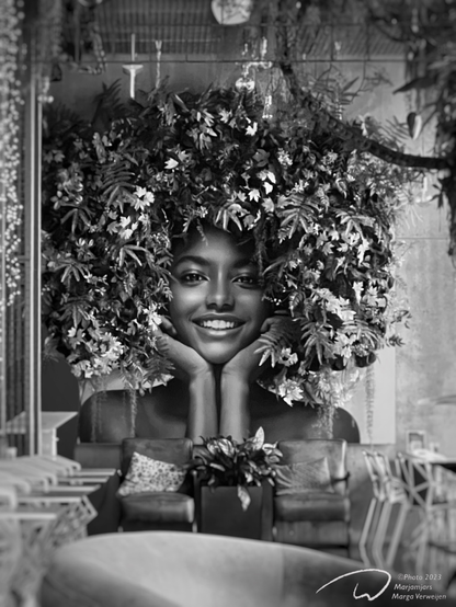 Interior of a hotel bar with a large photograph of a black woman on the wall with leaves and flowers arranged around her face, simulating her hairstyle.