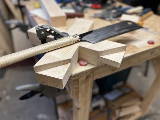 The wooden x is now lying flat on the workbench and clamped to it. The Japanese dozuki saw is lying on top of it. One of the four tenons is cut out. Another one only half way.