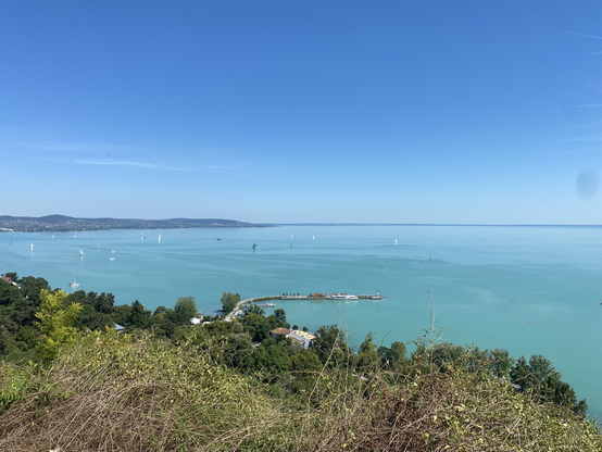 Uitzicht vanaf de kerk bij Tihany. Je ziet het Balatonmeer met op de voorgrond bomen en aan de linkerkant de heuvels.