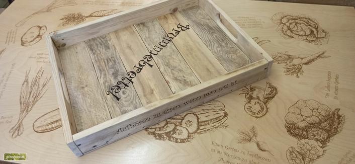 Das Tablett liegt auf einer ebenfalls gravierten Tischplatte.