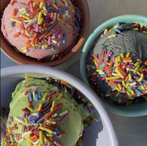 Fifty Licks color photo showing 3 bowls of w single scoop of pink, green, blue ice cream wearing rainbow sprinkles