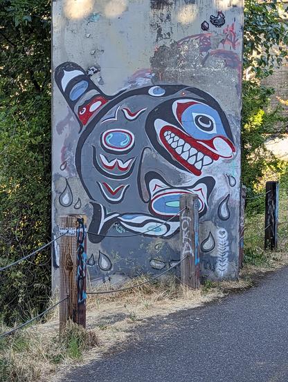 A bridge pillar painted with a stylized orca in the style of pacific northwest naitive.