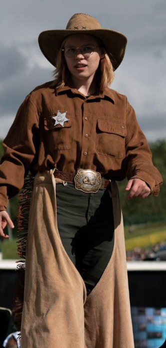 Person in a sheriff’s outfit (chaps, leather shirt, cowboy hat) on stilts.