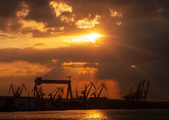 Sunset over shipyard with a lot of godrays piercing the clouds.