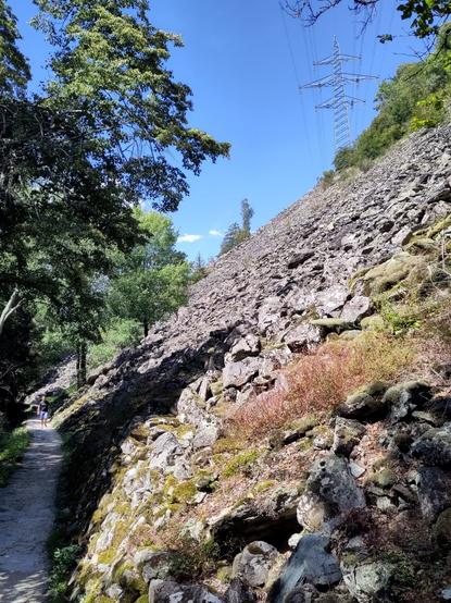 Foto. Ein Weg am Fusse einer Geröllhalde.