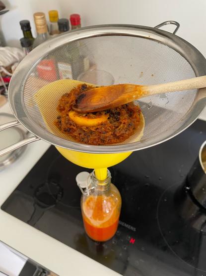 Straining the boiled mixture into a bottle.
