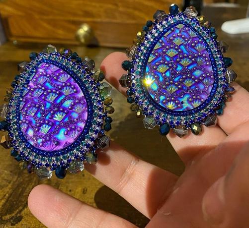 Gorgeous oval shaped, beaded purple beaded earrings in Sara's hand.
