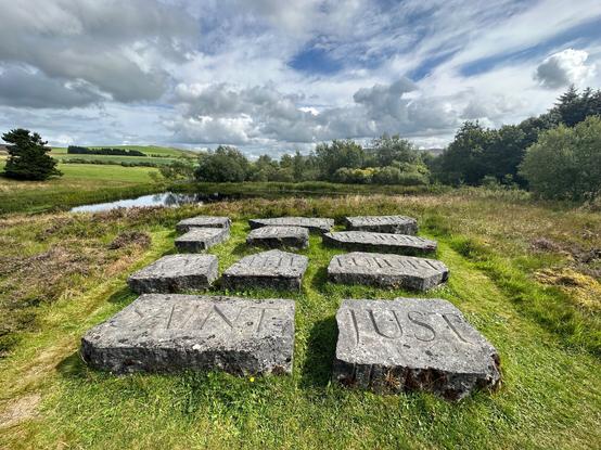 wide angle view of artwork of stone slabs with lochin background. Blue sky with cumulus clouds