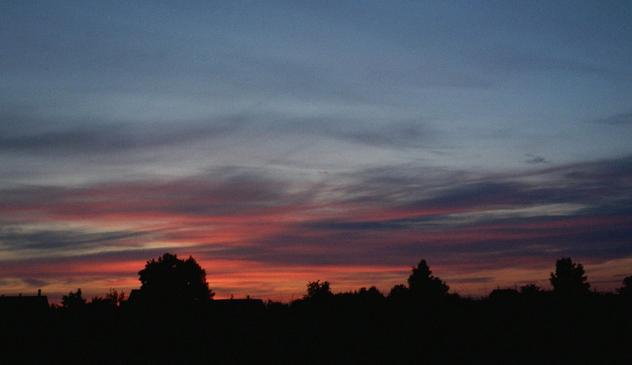 silence. village houses and trees at sunset. shades of red,orange and purple in the sky