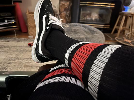 My elevated crossed legs with my black socks with red and white stripes at the top and my Vans shoes.