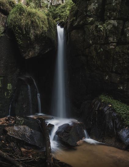 Small waterfall in the forest. Moss grows on the rocks.