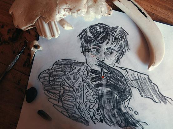 A black and white sketch of a video game character Daniil Dankovsky smoking. The end of the cigarette is red. There's also some redness on his right cheek. On the photo of a sketch one can find animal bones and metal details and stones.