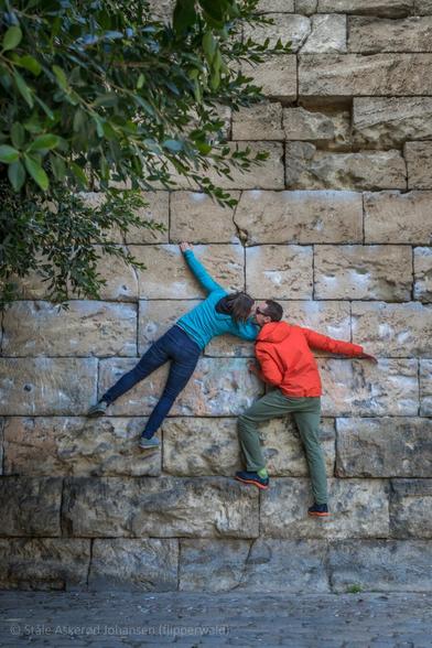 Two people climbing a wall in Sevilla. They kiss.