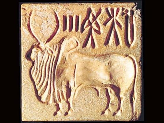 Image of a Indus Valley seal from Mohenjodaro. The seal bears the image of a bull and some text in Indus Valley Script.
