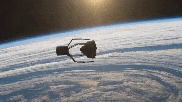 A space craft shaped like big, four fingered, claw grabs hold of a cone shaped piece of space debris. In the background is the clouds and sea of Earth, showing a section of horizon and a thin line of atmosphere.
