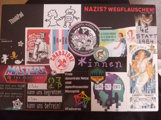 Ein fast vollständig beklebter Laptopdeckel. Mittig oben ist ein Sticker von Kolle-Mate, auf dem die 4 Maskottchen der Brausesorten abgebildet sind und auf dem: "Allerta, Allerta! Kollektiv gegen Sexismus", steht.