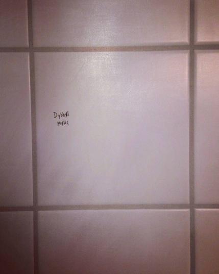 Picture of a white bathroom tile. Someone has written a tiny message in permanent marker: “Dybbøl Mølle” (“Dybbøl Mill”)