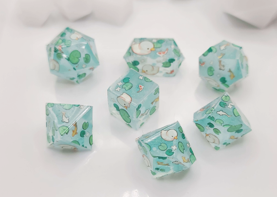 7 dice "blanks" that are a very light sparkly blue. They have lily pads, ducks, and fish all over them.