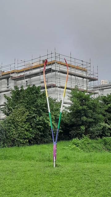 Pince à épiler géante (3 m) posée dans une pelouse du Havre, intitulée "Attrape nuages" avec un immeuble en construction en arrière plan