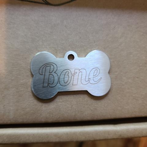 The word "Bone" is etched into a dogbone shaped, stainless steel dog tag.