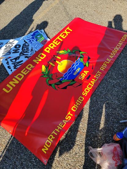 Red banner. 
Top text: Under no pretext
Centered is the Northeast Ohio SRA Chapter symbol
Bottom text: Northeast Ohio Socialist Rifle Association