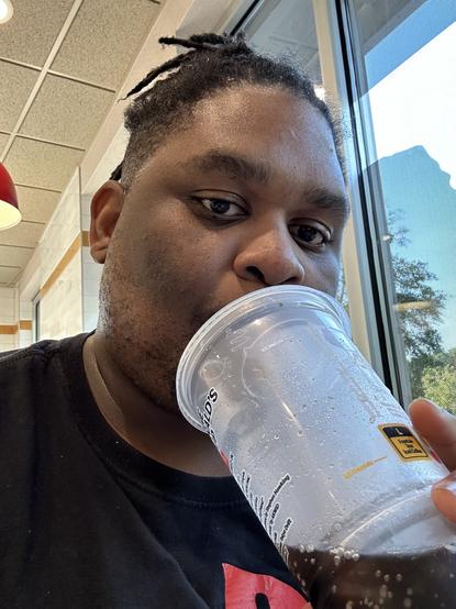 Me sipping some Diet Dr Pepper from a plastic cup while looking into camera.