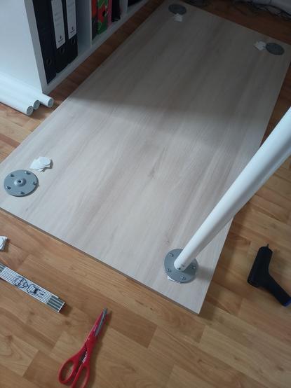 Schreibtischplatte, teilweise montierte Beine. Es liegt Werkzeug herum.