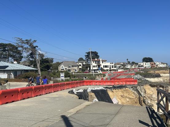 Photograph i took on 23rd August on West Cliff Drive in Santa Cruz, showing erosion taking away sections of the road, res ripraps around, houses on the left, blue sky