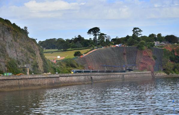 Train going past a sandstone cliff.