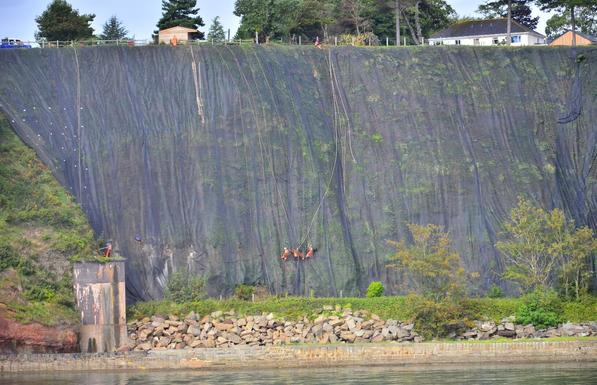 Workers working on cliff face to stabilize the slope.