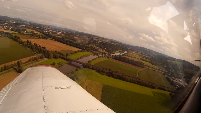 Overwing view out of a Piper PA28 flying over the Weser river with railway and motorway bridges