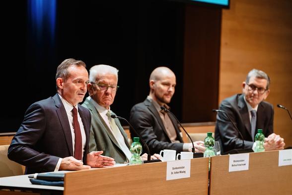 Volker Wissing sitzt auf dem Podium neben Winfried Kretschmann, Jonas Andrulis und Reinhold R. Geilsdörfer.