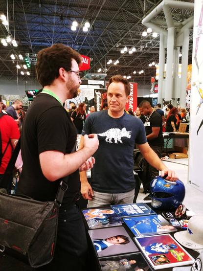 A nerdy guy speaks to David Yost, the actor for Bill from Mighty Morphin' Power Rangers, at a comic book convention.