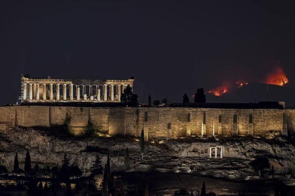 El Partenón de noche, con incendios en montes lejanos