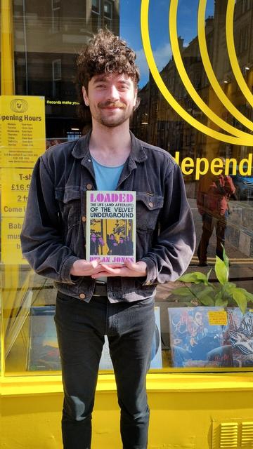 Thorne Records staff holding a copy of Loaded, Dylan Jones's new book about the life of the Velvet Underground, outside their bright yellow record store.