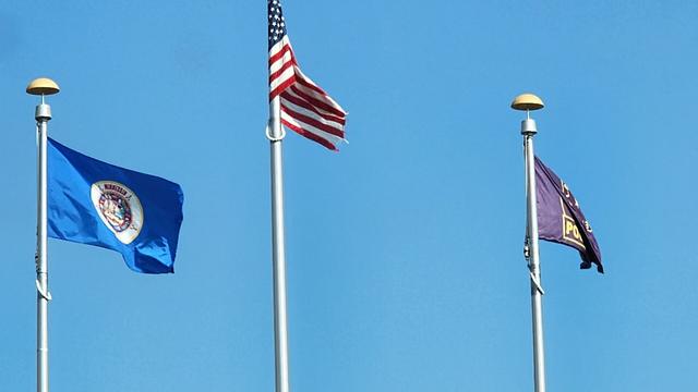 An upside down Minnesota flag flies next to US flag and a police flag against a #bluesky