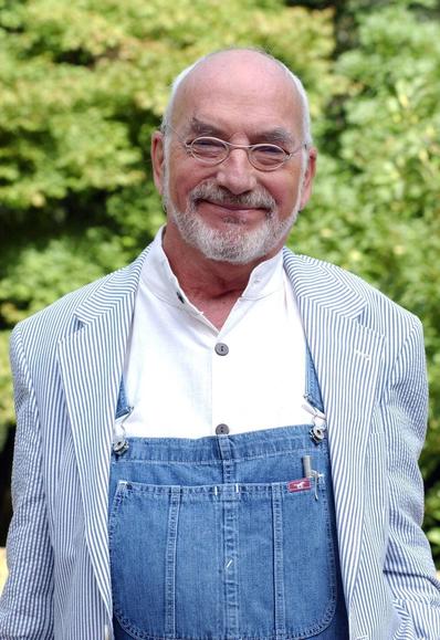 Peter Lustig, a [sadly deceased] moderator for a popular Children's TV Program named "Löwenzahn" [Dandelion] wearing his iconic blue jean dungarees over shirt.