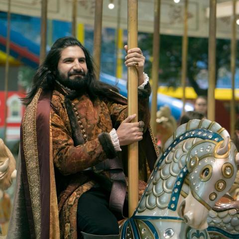 Nandor the Relentless (from the vampire mockumentary What We Do in the Shadows) looking fulfilled while riding a merry-go-round