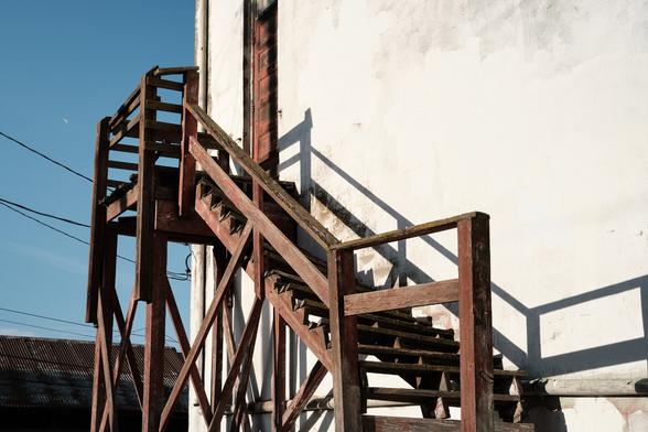 A set of wooden stairs on the outside of a building. Warm morning light.