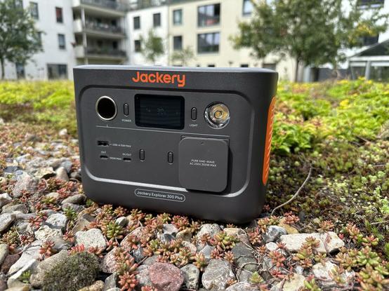 Der Jackery Solargenerator 300 Plus steht auf Steinen vor einem Häuserkomplex.