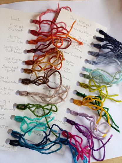 Photo shows some shade cards of different coloured yarn. There are 2 cards, and the colours are written in pencil alongside the yarn sample.