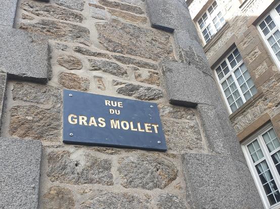 Panneau de rue portant l'inscription "rue du gras mollet"